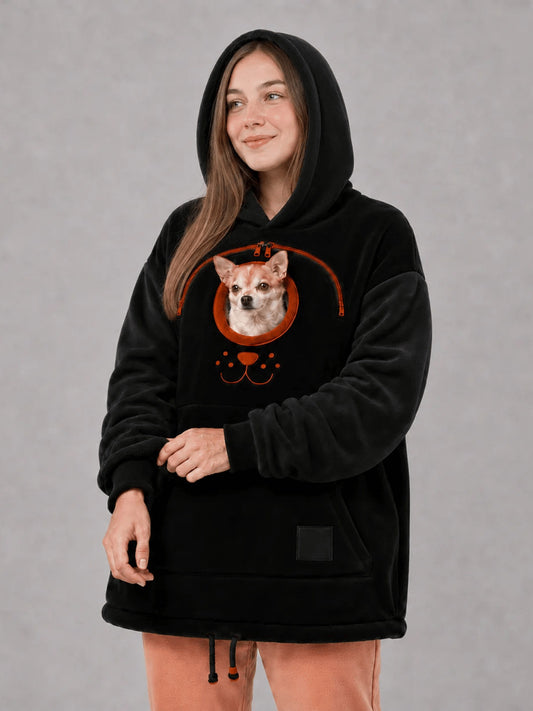 Black oversized fleece pet carrier hoodie with the hood up and a small dog in the front carry pouch