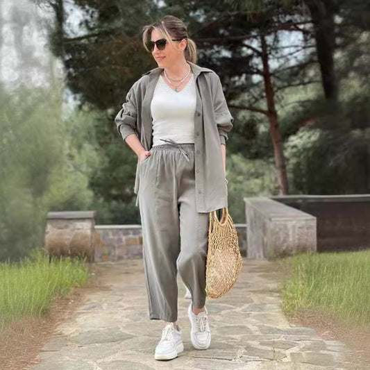 Grey shirt and wide-leg cropped trouser two-piece set worn open over a white top on a garden path