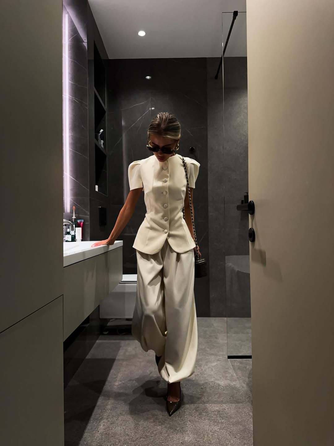 Black jacket and wide-leg trouser set photographed indoors against tiled walls