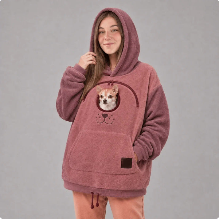 Pink fleece pet carrier hoodie shown front on with a small dog's head through the chest opening