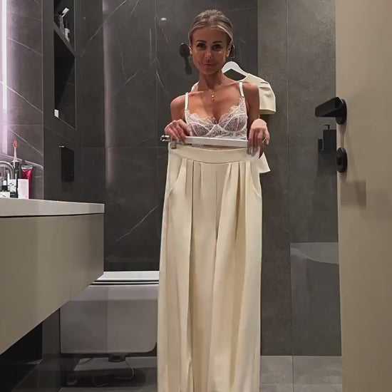Video showing the high-waisted wide-leg trousers held up at the waist, with the matching peplum jacket on a hanger