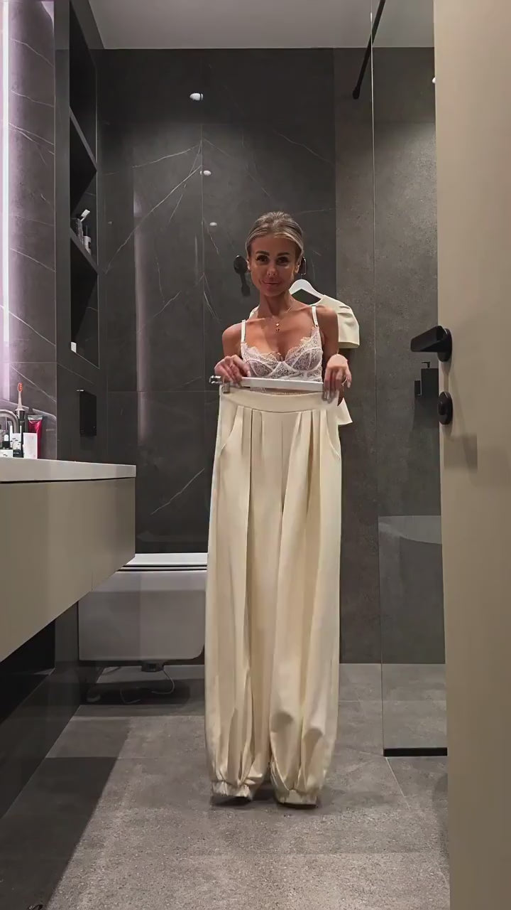 Video showing the high-waisted wide-leg trousers held up at the waist, with the matching peplum jacket on a hanger